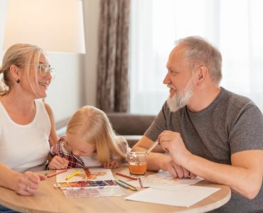 Grandparents and a child bond over painting at a cozy home setting, smiling and focused.