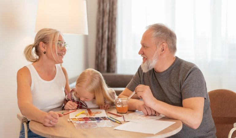 Grandparents and a child bond over painting at a cozy home setting, smiling and focused.